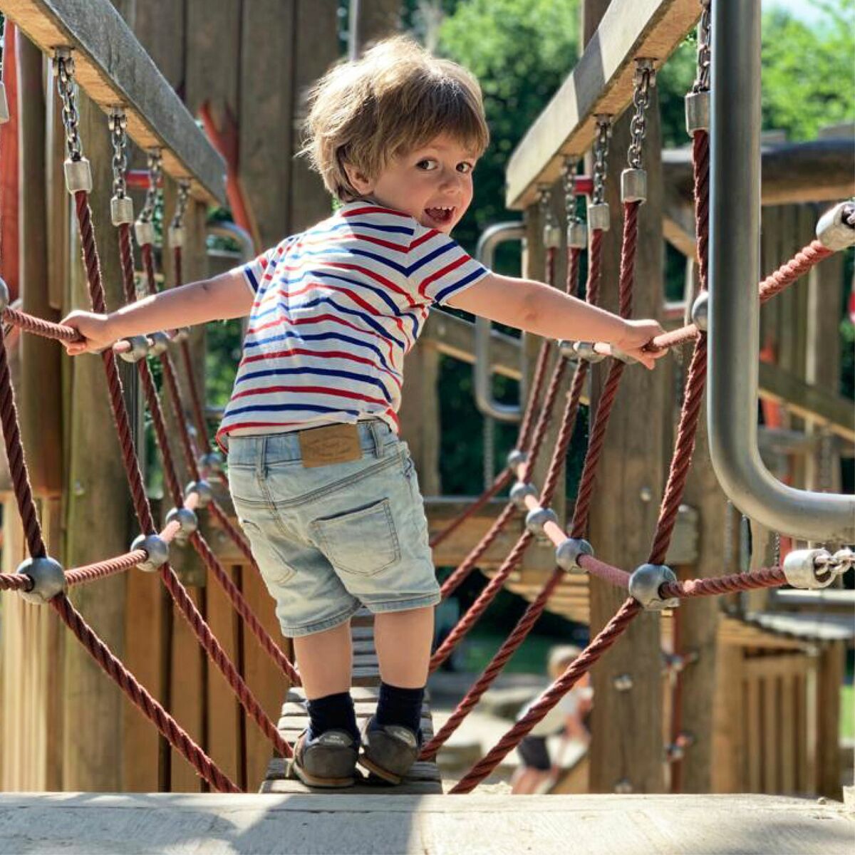 Kindergarten-Kind klettert auf dem Spielplatz